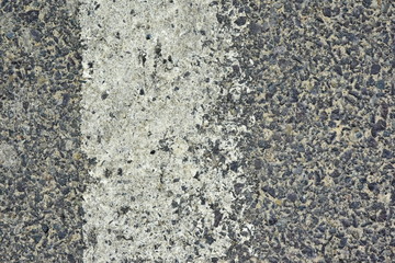 A worn white reflective road marking close-up on an asphalt pavement