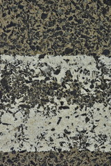 A worn white reflective road marking close-up on an asphalt pavement