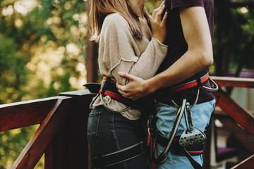 Crop couple in safety harnesses kissing in park