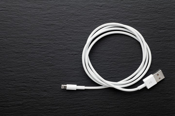 White USB mobile charging cable on black stone