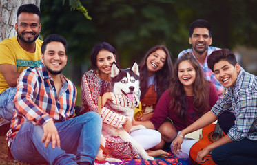 portrait of happy friends chilling together with pet dog in park