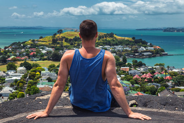 Fototapeta na wymiar Man sitting on the edge of view point in Auckland, New Zealand
