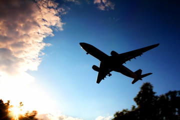 The silhouette of a large plane flies against the background of a cloudy sky. Takeoff Landing Sunset