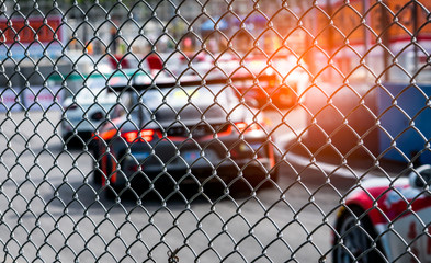 Motor sport car racing on asphalt road. View from the fence mesh netting on blurred car on...