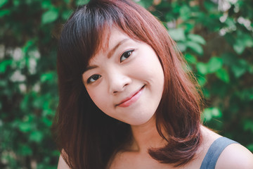 Close up of young pretty Asian woman in blue dress with garden background.