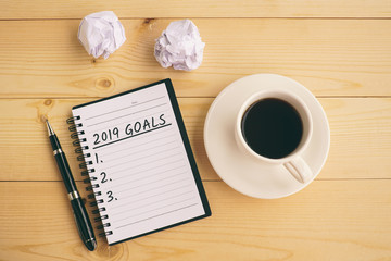 2019 goals text on notepad with coffee, pen and crumpled paper.