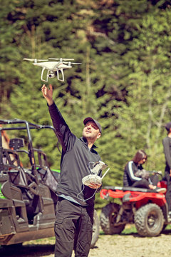 A drone pilot prepares to catch a descending drone quad chopter about to land still in flight.