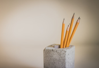 Yellow wood pencils and concrete cube