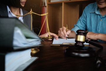 Business woman and lawyers discussing contract papers with brass scale on wooden desk in office....