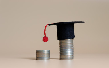 Two pile of coins and miniature graduation cap. The concept of student loans.