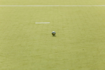Running ball on grass in field hockey game.