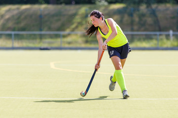 Young hockey player woman with ball in attack playing field hockey game