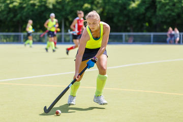 Obraz premium Young hockey player woman with ball in attack playing field hockey game