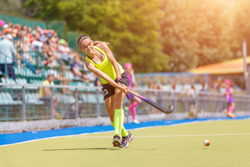 Young hockey player hit the ball in field hockey game