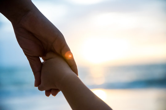 soft focus parent hold the little child hand during sunset, warm tone.