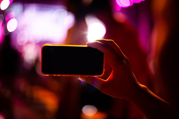 People taking photographs with smart phone during Live music concert and crowd in background