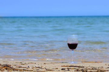  glass of red wine on the beach seashore in summer on sunny day with blue sea. 