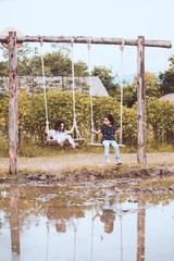Two cute asian child girls playing swings together in the farm at countryside with fun