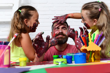 Girls drawing on man face skin with colorful paints