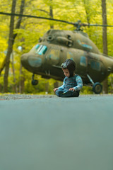 Kid sitting at helicopter on natural background