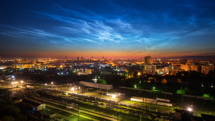Fototapeta na wymiar Noctilucent clouds over the city downtown at summer night