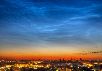 Noctilucent clouds over the city downtown at summer night