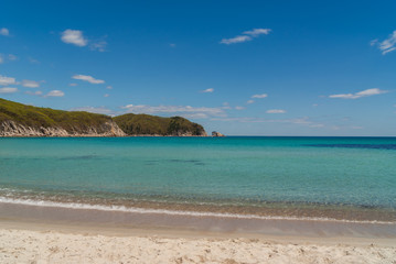 Fototapeta na wymiar Beautiful blue water bay, empty beach, crystal clean water, blue sky on sunny day