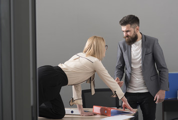 Business woman seduce boss in office. Business woman on desktop look at bearded businessman, sexual...