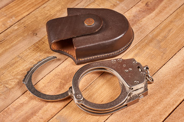 real police handcuffs with case on wooden background