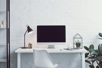 computer, white table, chair and plants in modern workplace