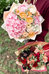 Two Beautiful summer bouquet. Arrangement with mix flowers. Young girl holding red and pink flower arrangements . The concept of a flower shop. Content for the catalog
