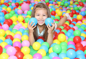 Fototapeta na wymiar Cute girl playing among plastic balls
