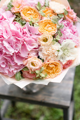 Beautiful pink summer bouquet on wooden table. Arrangement with mix flowers. The concept of a flower shop. Content for the catalog