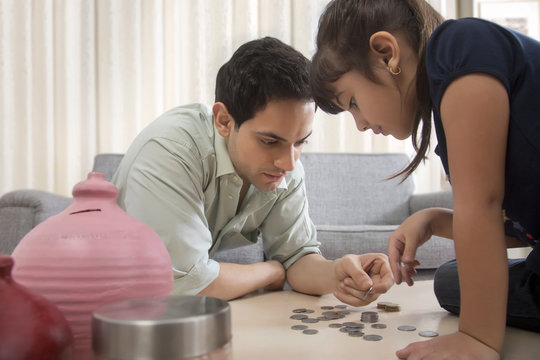 Father and daughter counting piggy bank coins
