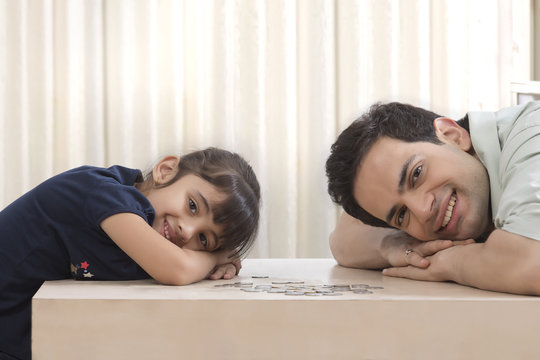Father and daughter leaning on table with coins