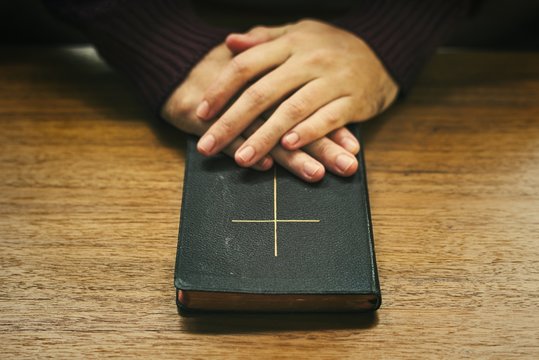 Hands over the bible on a wooden table