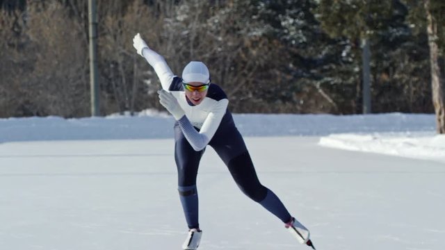 Locked down shot of motivated sportswoman practicing speed skating when training on outdoor ice rink in winter