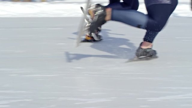 Legs of two unrecognizable professional athletes beginning speed skating race on outdoor ice rink in winter