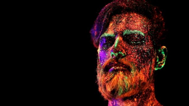 Concept. Portrait of a bearded man. The man is painted in ultraviolet powder