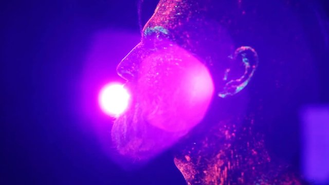Concept. Portrait of a bearded man. The man is painted in ultraviolet powder