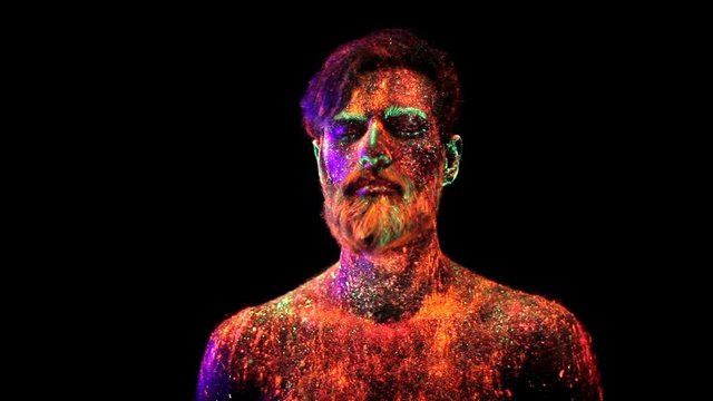 Concept. Portrait of a bearded man. The man is painted in ultraviolet powder