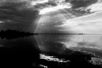 Perfectly symmetric and spectacular view of a lake, with clouds, sky and sun rays reflecting on water