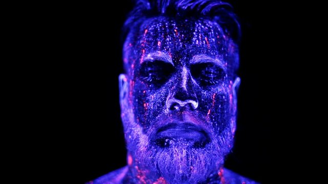 Concept. Portrait of a bearded man. The man is painted in ultraviolet powder