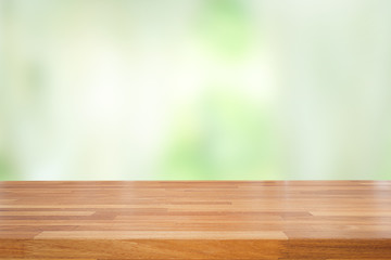 Empty of wood table top on blur of abstract green from garden with sunlight and curtain window