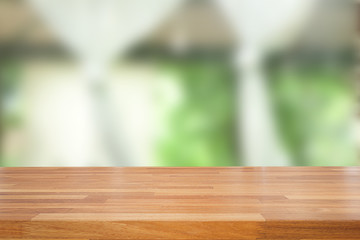 Empty of wood table top on blur of abstract green from garden with sunlight and curtain window