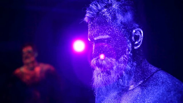 Concept. Portrait of a bearded man. The man is painted in ultraviolet powder