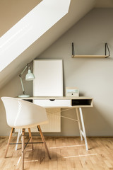 White chair at desk with lamp and poster in bright workspace int