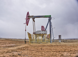 The beam pumping unit is homework, sunset in oil field. Oil pump oil rig energy industrial machine...
