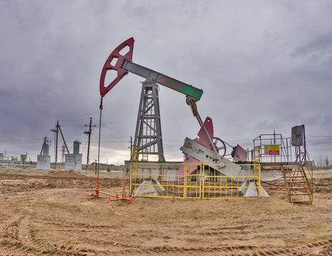 The beam pumping unit is homework, sunset in oil field. Oil pump oil rig energy industrial machine for petroleum. The pumping unit as the pump installed on a well. Equipment of oil fields.