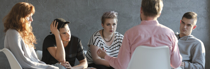 Difficult teenagers listening to psychotherapist during meeting of support group